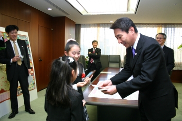 写真：大臣から名刺を受け取る服部さん